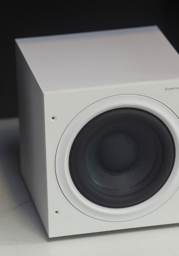 O subwoofer, também em branco, fica apoiado sobre o piso
