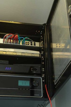 O móvel de parede dá acesso às conexões dos aparelhos, entre eles um amplificador multiroom de 8 zonas