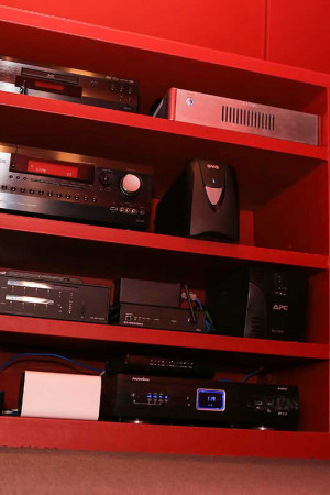 Os equipamentos do minicinema foram discretamente instalados em um móvel vermelho baixo, que fica num espaço anexo</br> ao minicinema.