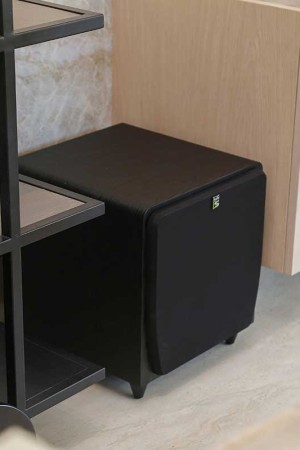 No home theater de 40m2, o subwoofer fica do lado esquerdo, num vão entre dois móveis.