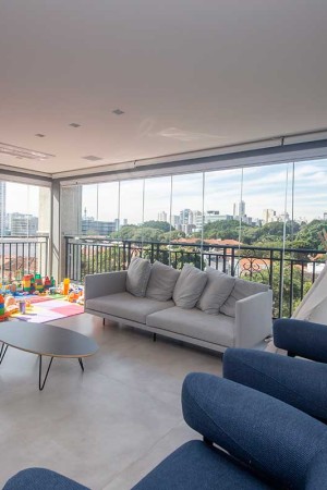Vista ampla da sala de estar sonorizada (com caixas acústicas no teto); a pequena brinquedoteca faz a alegria do filho pequeno.