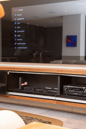 : A TV de 75” está embutida no painel espelhado, uma tecnologia que dá um novo ar à sala.