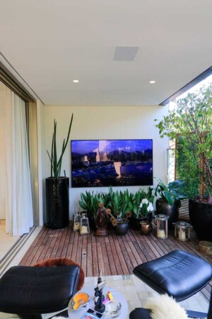 Detalhe da varanda, com outra TV de 85”, que dá acesso ao espaço gourmet e à piscina.
