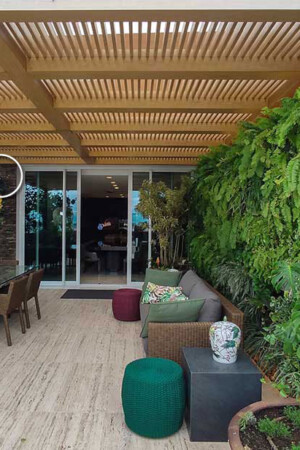 Na varanda, quatro caixas para áreas externas se confundem com a decoração e o jardim vertical.