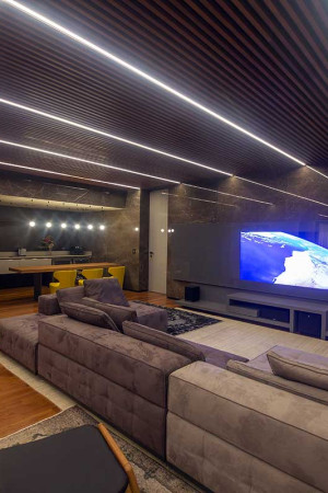 Aqui, uma das salas íntimas, também com TV Espelho, destacando o design da iluminação no teto.