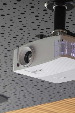 Projetor 4K preso ao teto através de suporte; as luzes do teto são acionadas pelo controle remoto.