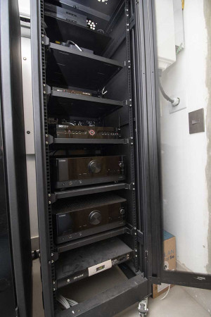 Num cômodo separado, ao lado da garagem, o rack acomoda os eletrônicos que atendem</br> toda a residência.