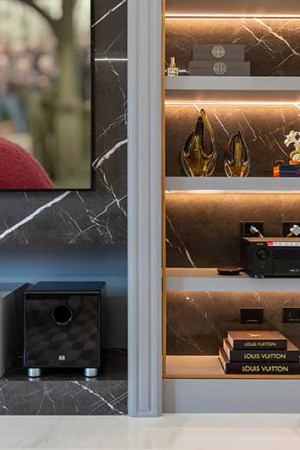 O painel de mármore abriga a TV de 75”, a estante e contém as vibrações do subwoofer de 10”.