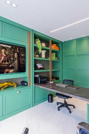 O escritório, com mesa de mármore integrada ao móvel de madeira que tem nicho especial para a TV de 65”.