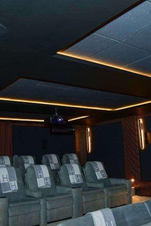 Detalhe do teto, com iluminação e revestimento típicos de uma sala de cinema.