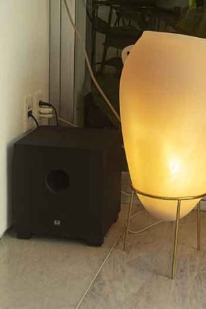 Detalhe do subwoofer num canto do living; na varanda, há um outro sub oculto no teto.