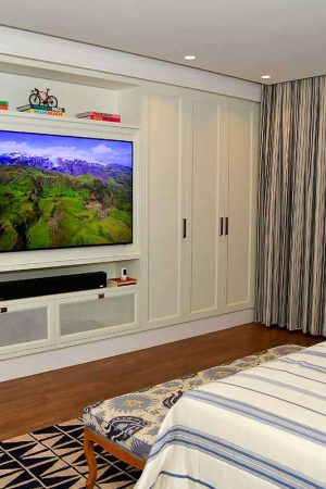 Numa das suítes, a TV de 75” foi embutida num nicho da parede; a soundbar é de nível high-end.