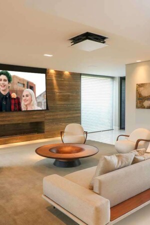 Living com projetor e tela retrátil de 119”, combinando discretamente com 4 caixas de teto.