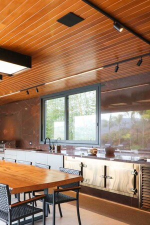 Vista da área gourmet, também com som e iluminação inteligente no teto; a TV tem 55”.